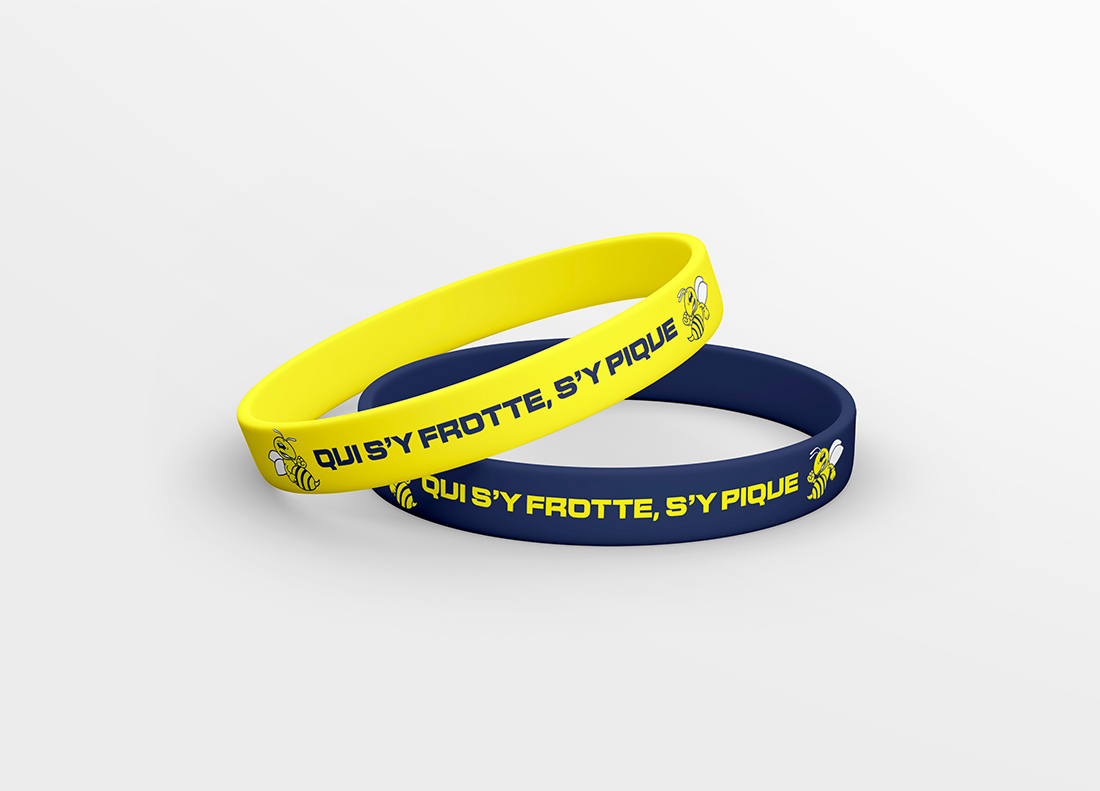 Deux bracelets en silicone de couleurs jaune et bleu avec le slogan "Qui s'y frotte, s'y pique" et le logo des Blue Bees. Parfaits pour les supporters de l'équipe.