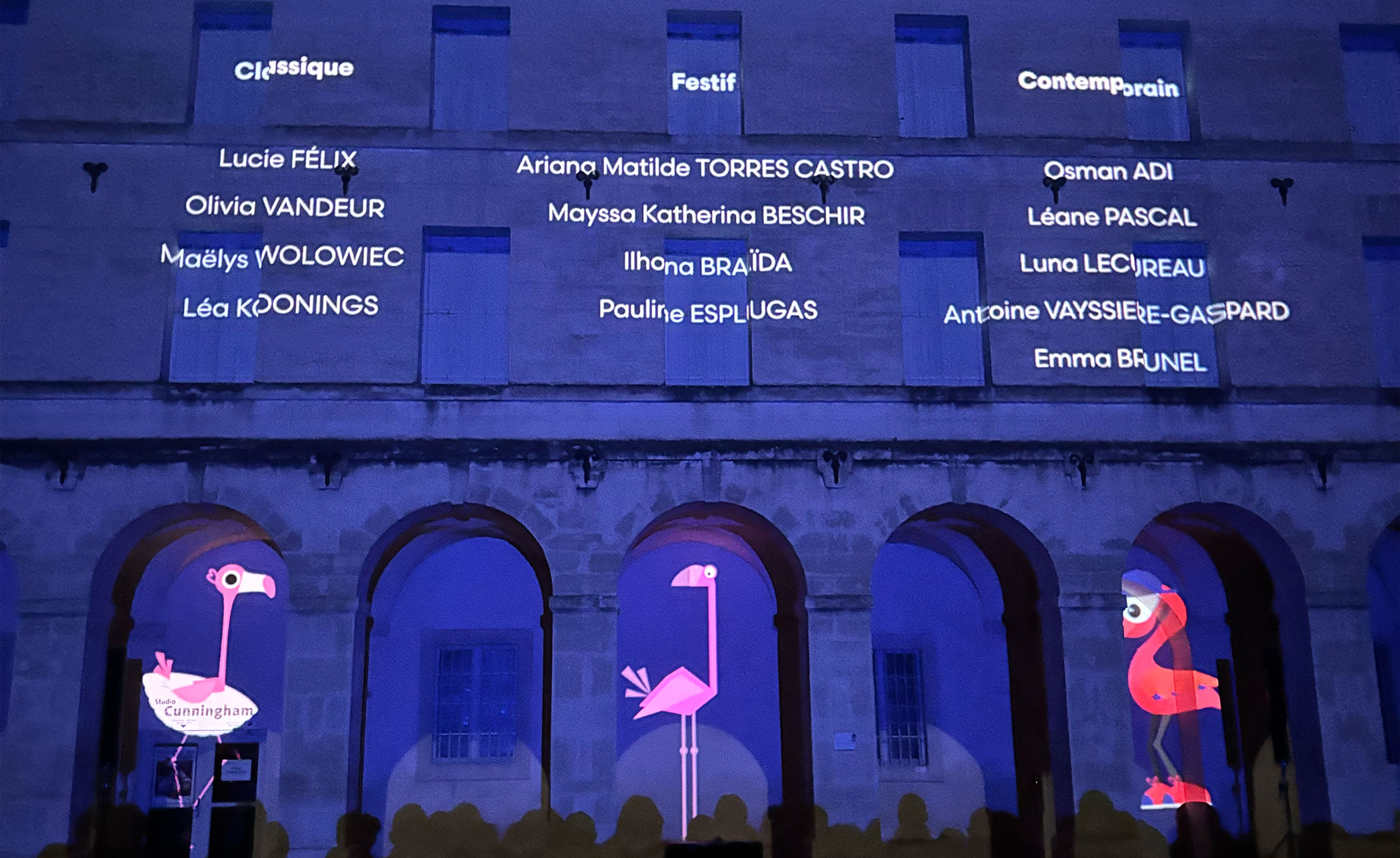 Façade de l'agora illuminée affichant les catégories Classique, Festif, Contemporain et les noms des étudiants ayant participé à coeur de ville en lumière.
