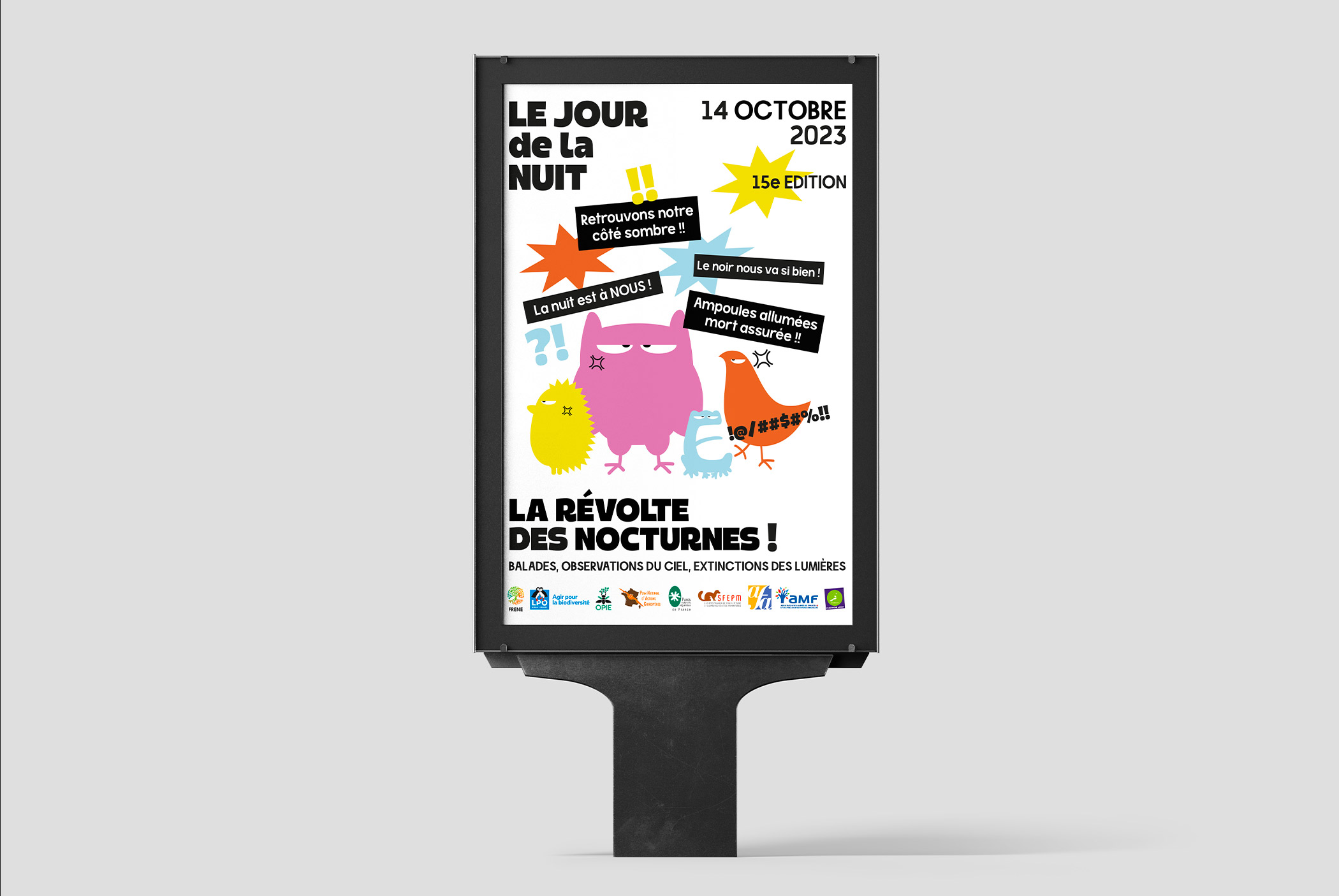 Affiche de l'événement "Le Jour de la Nuit" du 14 octobre 2023, 15e édition, affichée sur un panneau publicitaire. L'affiche présente des personnages d’animaux colorés et révoltés et des slogans pour la lutte contre la pollution lumineuse.